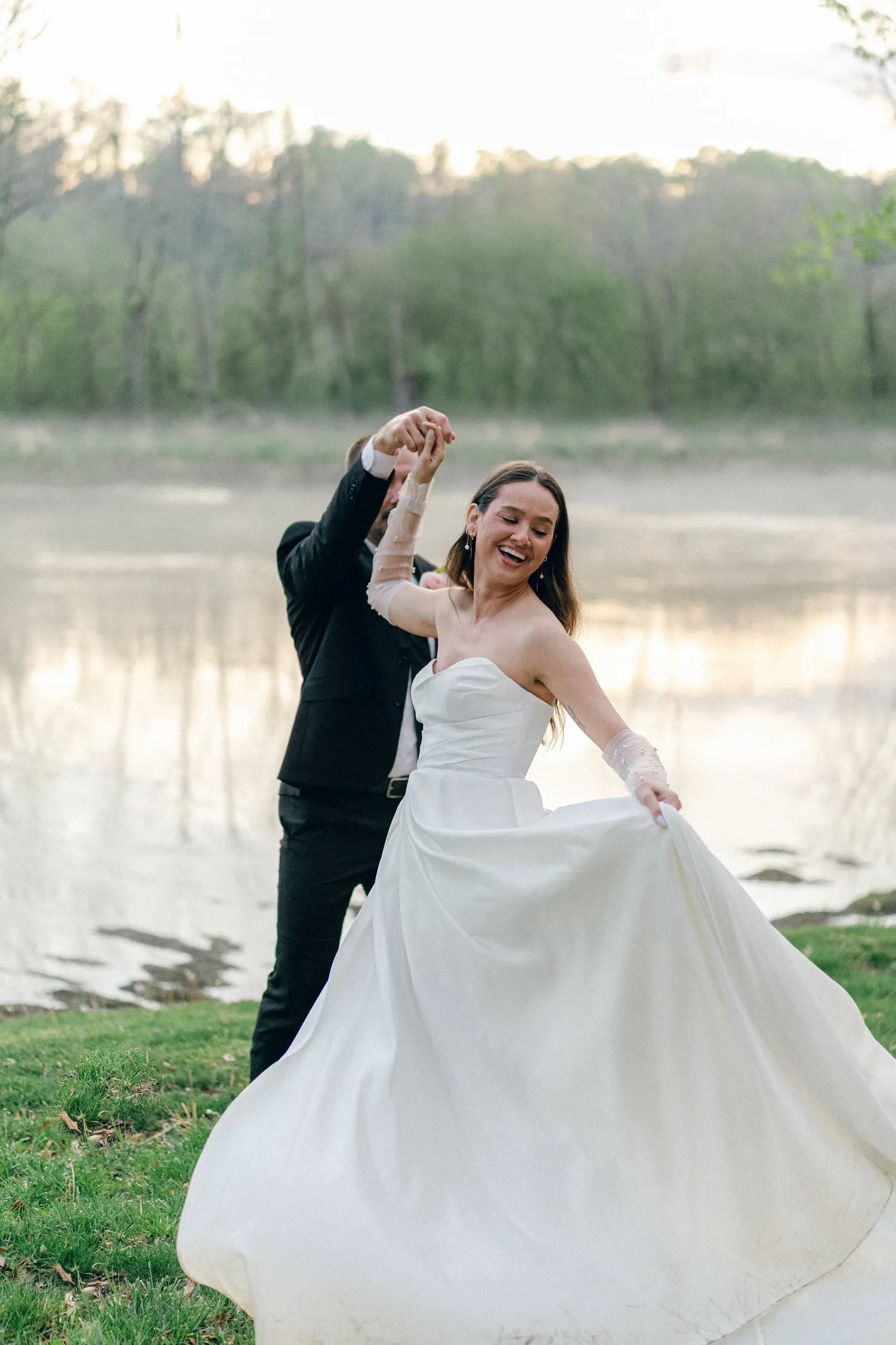 Bride twirling in her gown on the lawn at golden hour by the river