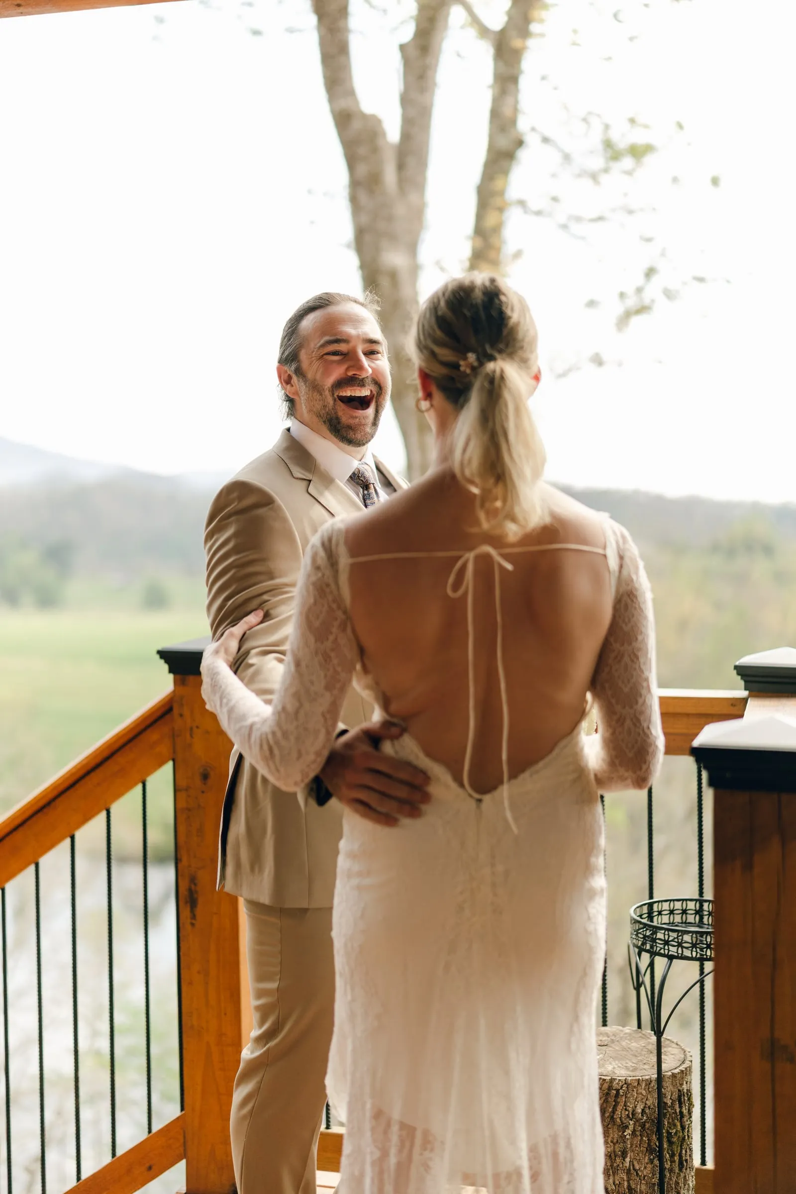 Groom laughing during a candid first-look moment on the cabin deck