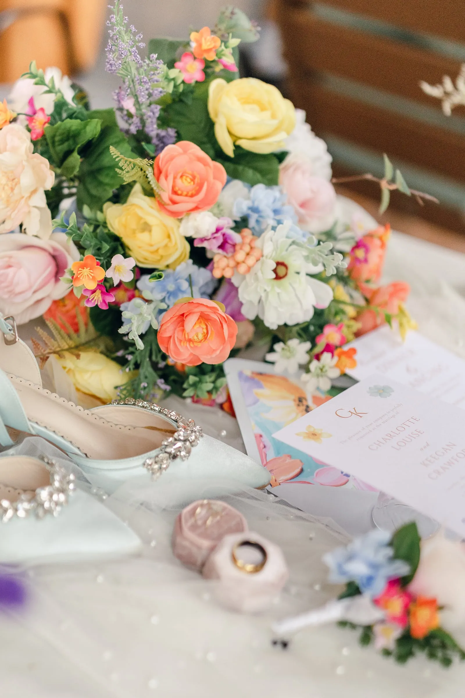 Styled bridal bouquet alongside rings, shoes, and the invitation