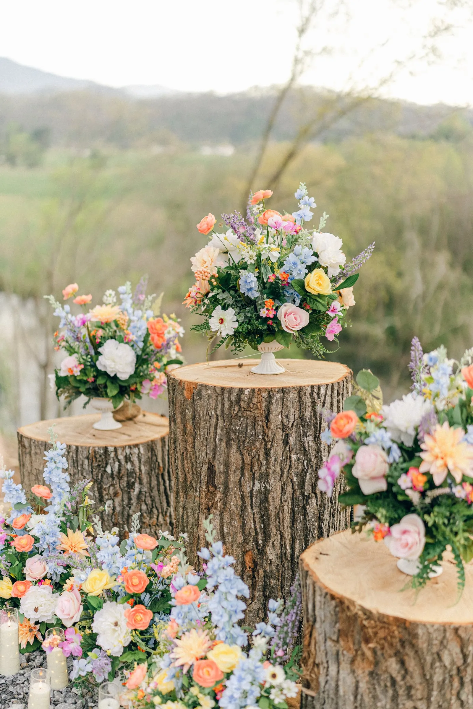 Wildflower arrangements on log rounds with the river valley behind