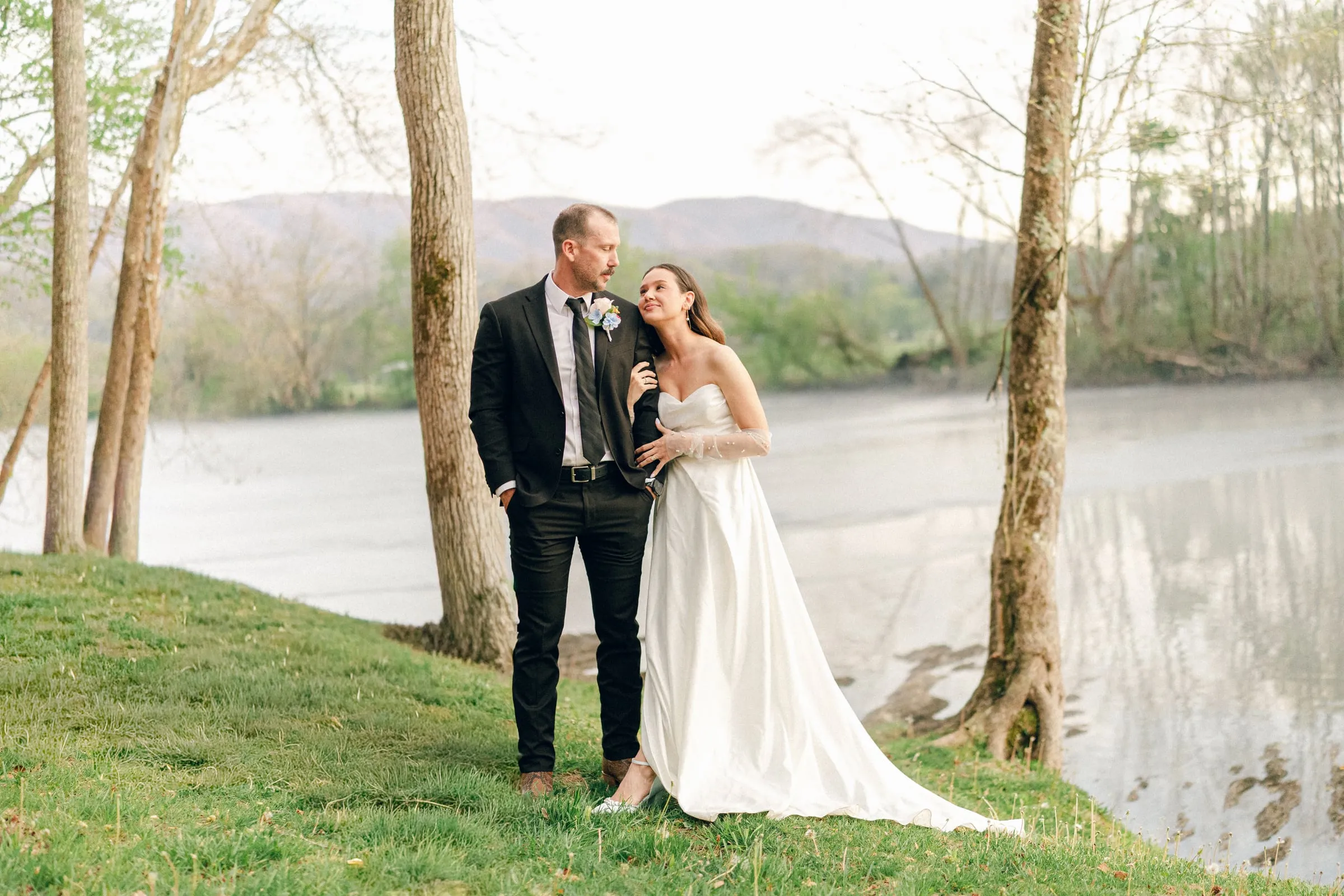 Wide portrait of the couple by the river framed by mountains