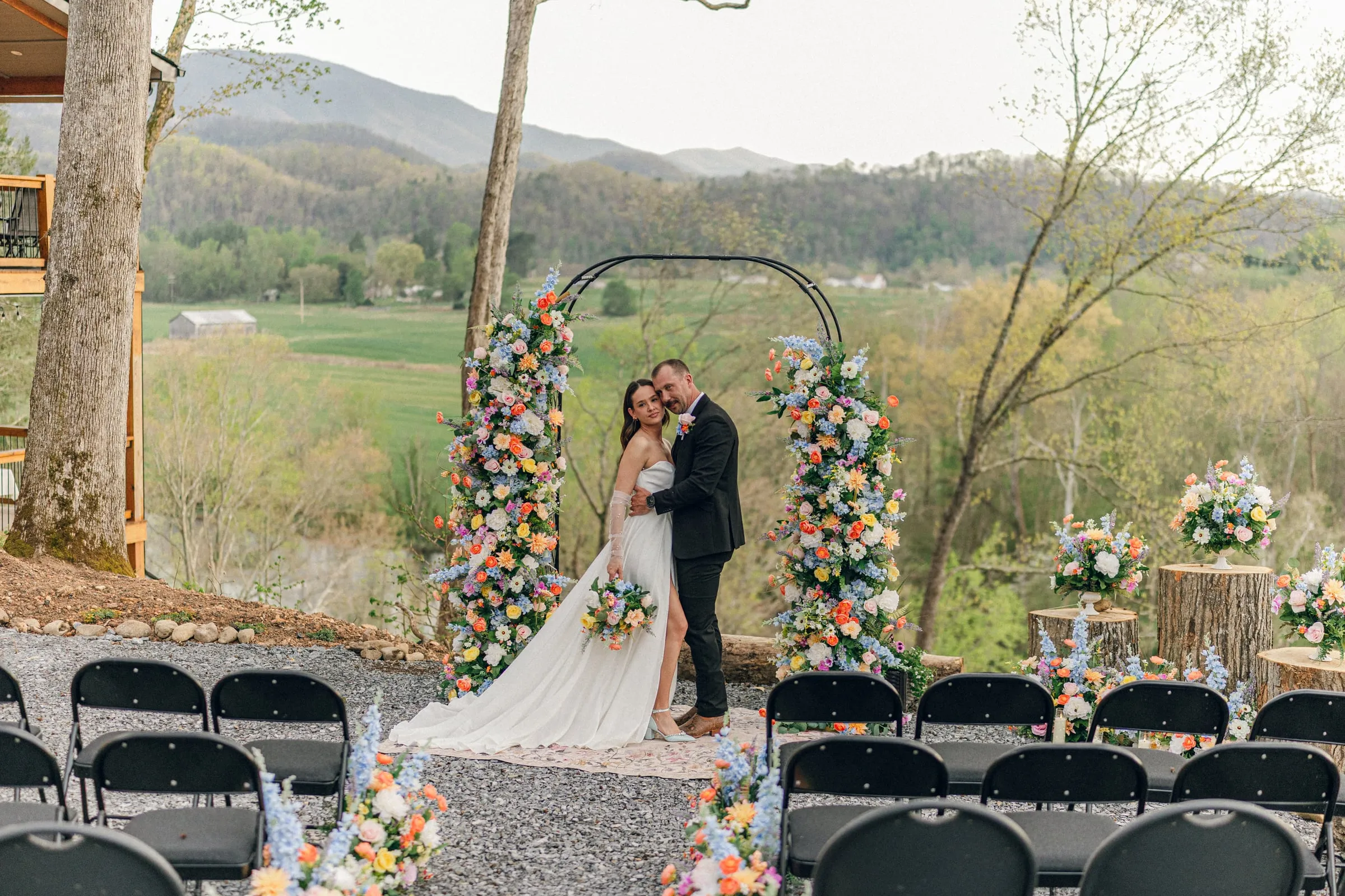 Couple at the floral arch with a sweeping mountain backdrop